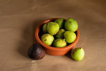top view figs in a clay bowl on a light brown background