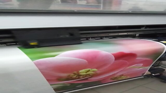 Large format printing machine in operation. Industry. Printing production. Printing on large format printer. printer prints photo. Modern print equipment. Colored print