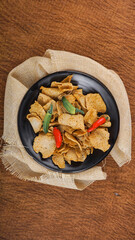 Flatlay view of Basreng, Indonesian traditional snack made from fried meatball with chilli powder for seasoning served on black plate.