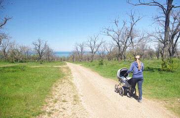 A young woman with a stroller in the park.