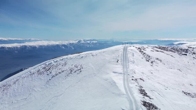Aerial view of a mountain slope used for freeride skiing. Visible snowcat tracks on the egde and summit. Ski and snowboard tracks on the powder snow.