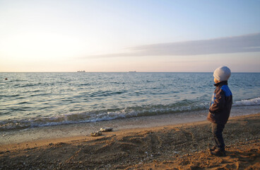 A little boy is standing on the beach