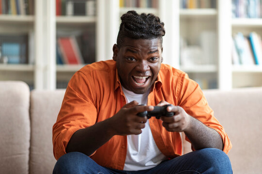 Handsome young black man playing video games at home