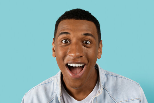 Cheerful funny young african american man with open mouth scream, look at camera