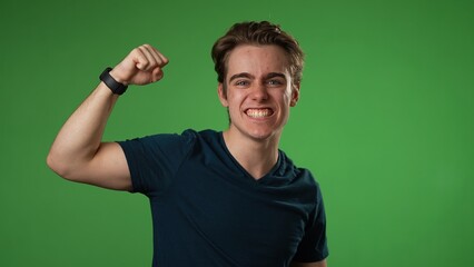 Excited jubilant overjoyed young man 20s doing winner gesture celebrate clenching fists say yes isolated on green screen background studio portrait 