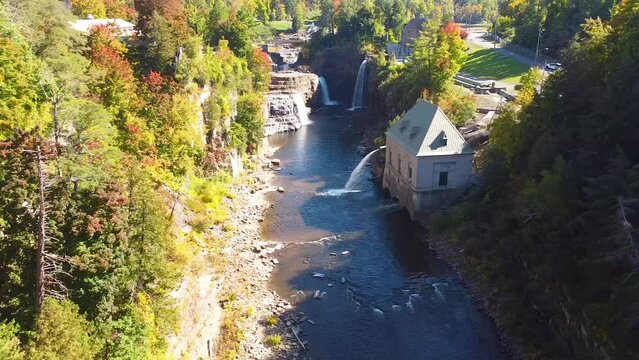 Aerial pan across stunning canyon with Hydroelectric power plant and multiple large waterfalls over cliffs