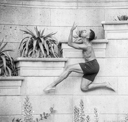 Young dancer positioned against a planter in an atheletic pose