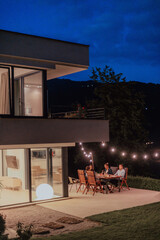 A group of young diverse people having dinner on the terrace of a modern house in the evening. Fun for friends and family. Celebration of holidays, weddings with barbecue.