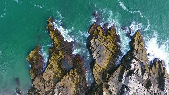 Aerial stationary view looking down on patch of rocky coasts in Maine with crashing waves