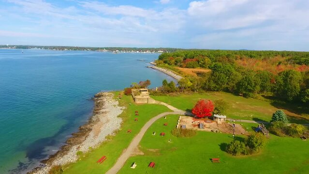 Aerial towards old military fort in park with view of Maine ocean and fall forests