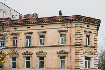 Brown facade of an old building with stucco. Dirty. Renovate. Restoration. Block. Demolition. Detail. Windows. Art Deco. Decay. Vintage. Decoration. Style