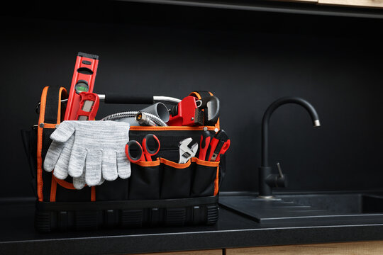 Plumber's tool bag on kitchen counter near sink
