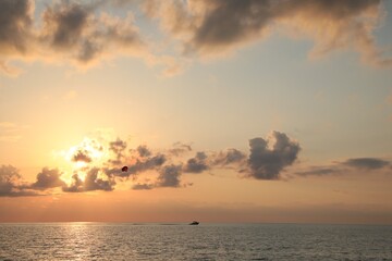 Picturesque view of beautiful sea and people parasailing at sunset