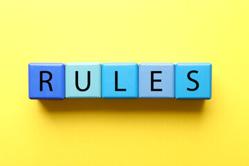 Word Rules made of wooden cubes with letters on yellow background