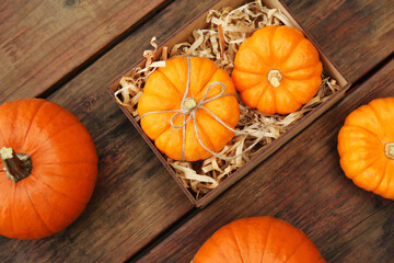 Crate and ripe pumpkins on wooden table, flat lay