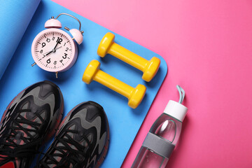 Sneakers, dumbbells, fitness mat and bottle of water on pink background, flat lay with space for...