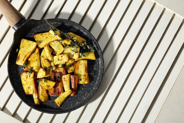 Delicious parsnips with thyme in frying pan on white wooden table, top view. Space for text