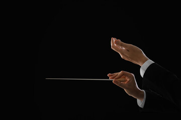 Professional conductor with baton on black background, closeup. Space for text