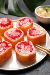 Delicious sushi rolls with salmon and tobiko on grey textured table, closeup