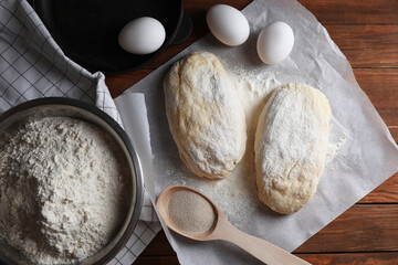 Raw dough, eggs and flour on wooden table, flat lay. Cooking ciabatta