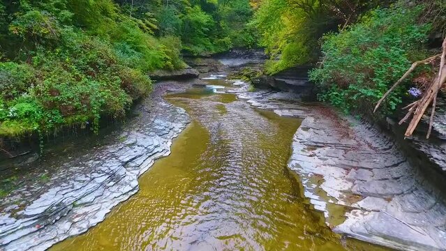 Aerial backwards to edge of huge waterfall from above with view down river and of forest