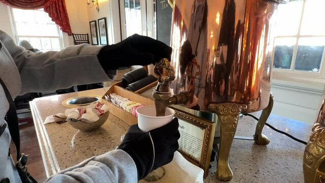 Woman pouring tea from ornate copper boiler at Abigail's Tea Room in Boston, close up