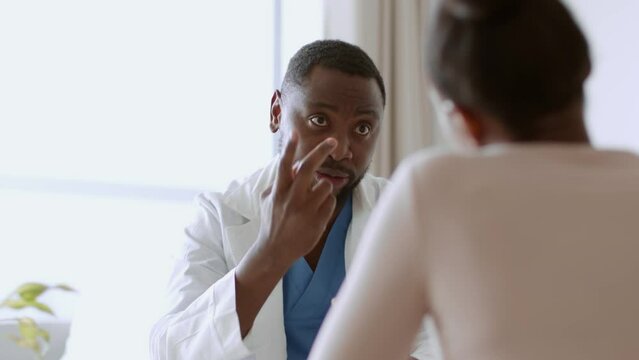 Friendly african american man doctor consulting young female patient, explaining her healthy lifestyle benefits