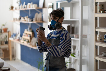 Female ceramic artist polishing pottery in workshop, female self-employed ceramist smoothing the...