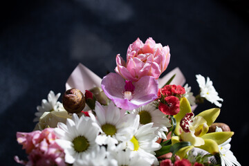 beautiful bouquet of different flowers close-up on a dark background - 553626572
