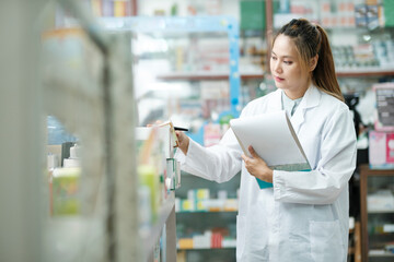 Female pharmacist checking stock inventory in pharmacy.