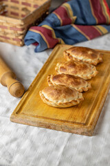 Traditional baked Argentinian empanadas on a board.