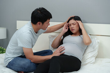 pregnant woman having headache with her husband on bed