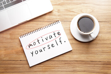 motivate yourself, motivational and inspirational words in notebook on table with laptop and cup of coffee.