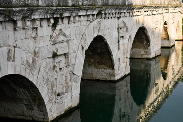 Arches of the Tiberius Bridge in Rimini, Italy, and their reflection in the Marecchia river