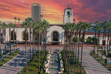 Union Station train station surrounded by office buildings, parked cars, tall lush green palm trees...