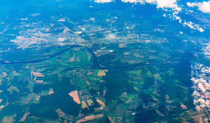 Aerial view from airplane window above green ground. View from the airplane window with beautiful clouds at sunrise