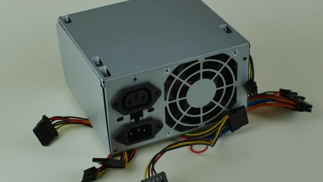 Close-up of a computer power supply on a light background with multi-colored wires and terminals. Broken computer power supply on a light background. The concept of repairing broken computers
