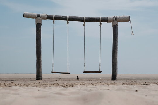 Swing on the sea beach and the black bird in the middle with the sky in the background - Powered by Adobe