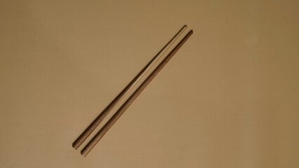 Two chopsticks on a empty brown background