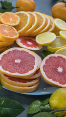 Fototapeta na wymiar sliced ​​citruses - grapefruit, orange, tangerine and lemon in a blue plate on a concrete background