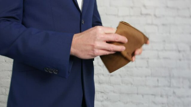 An empty wallet being opened by a business man showing that he has no money