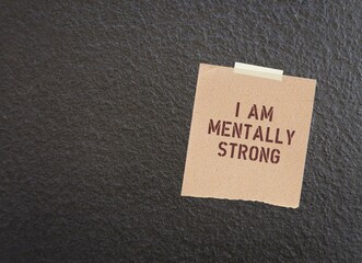Note stick on dark wall with text I AM MENTALLY STRONG, to remind self to have positive self-esteem...