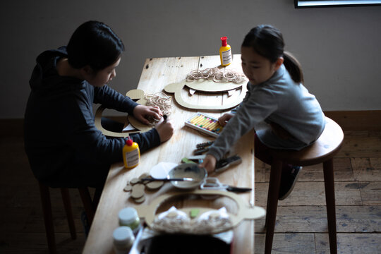 鬼のお面をテーブルの上で工作で作る姉妹