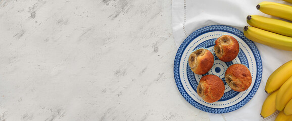 Tray with tasty banana muffins on light background with space for text