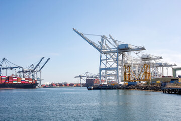 Fototapeta na wymiar A view of a port terminal where large cranes unload shipping containers from a cargo ship.