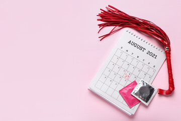 Calendar with marked day for sex, condoms and whip on pink background