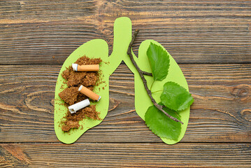 Paper lungs with cigarettes, tobacco and tree branch on wooden background
