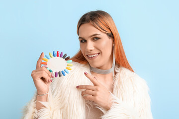 Young transgender woman with nail polish tips on blue background