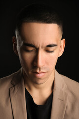 Young Asian man with closed eyes on black background