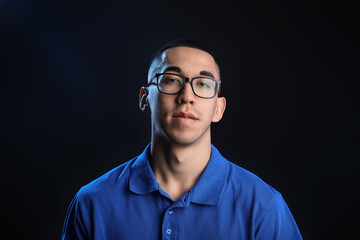 Portrait of young Asian man in eyeglasses on black background